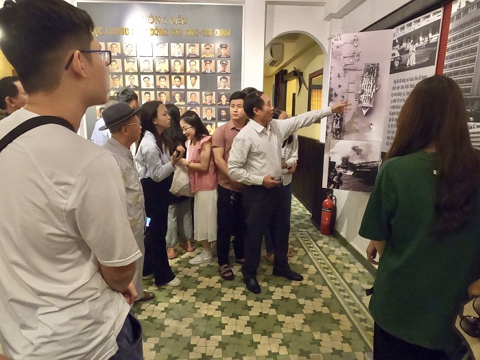Ông Nguyễn Quốc Độ (mặc áo sơ mi trắng, đứng giữa), đang thuyết minh cho du khách tham quan bảo tàng 